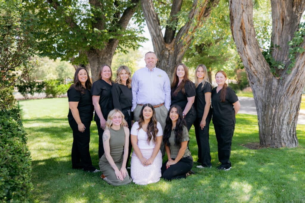 The Kiggins Family Dentistry team gathered outdoors under the trees