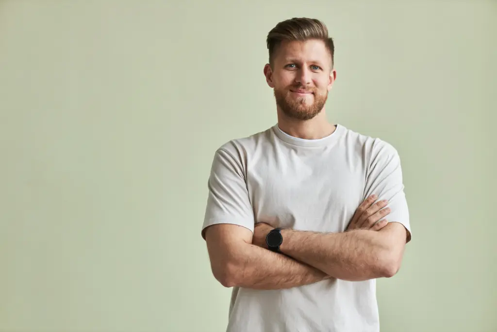 Smiling man in a white T-shirt standing with his arms crossed