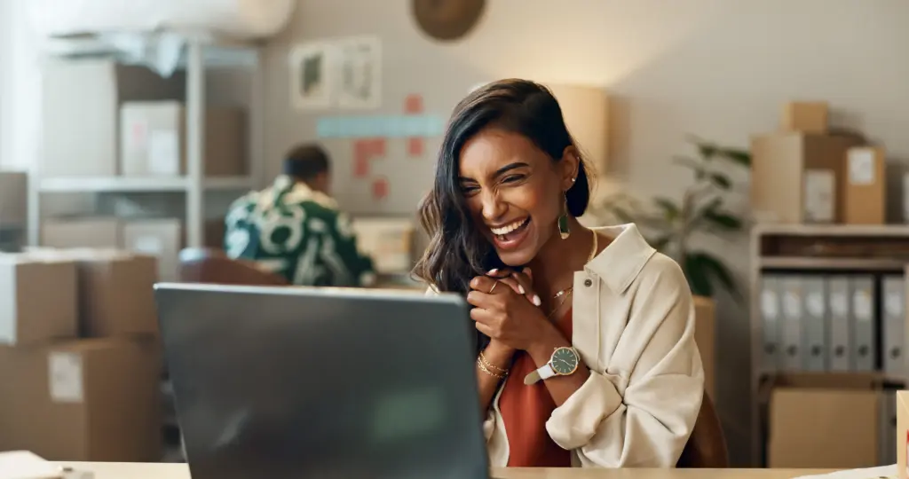 Woman laughing while working at a laptop
