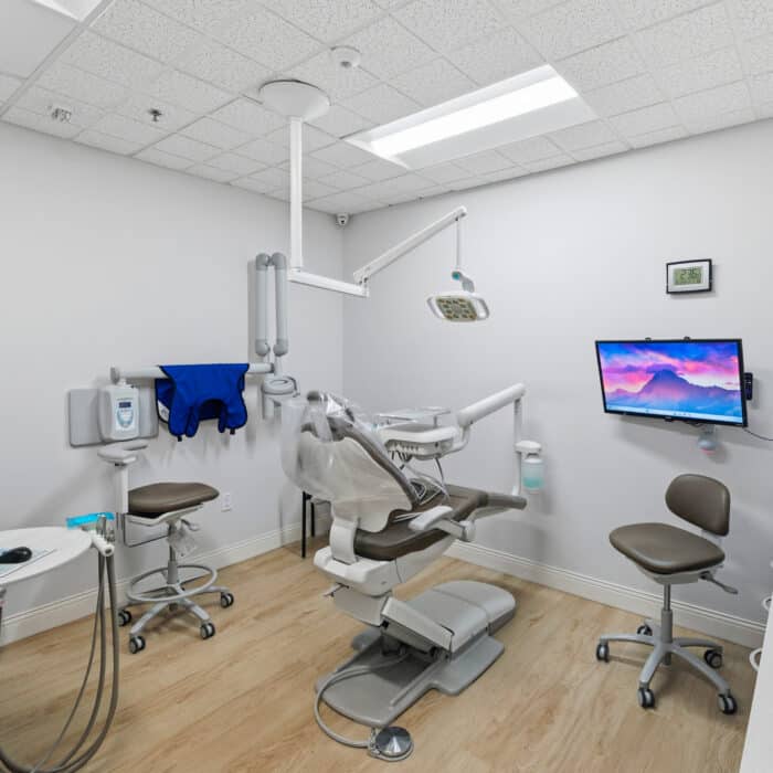 Treatment room with a dental chair, stools and a wall monitor