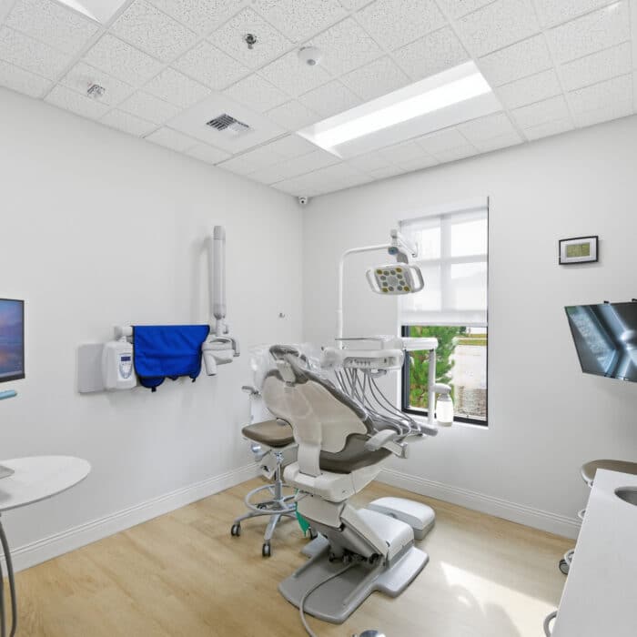 Treatment room with a dental chair and a ceiling-mounted monitor